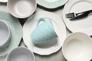 Beautiful ceramic dishware, cup and cutlery on light grey table, flat lay