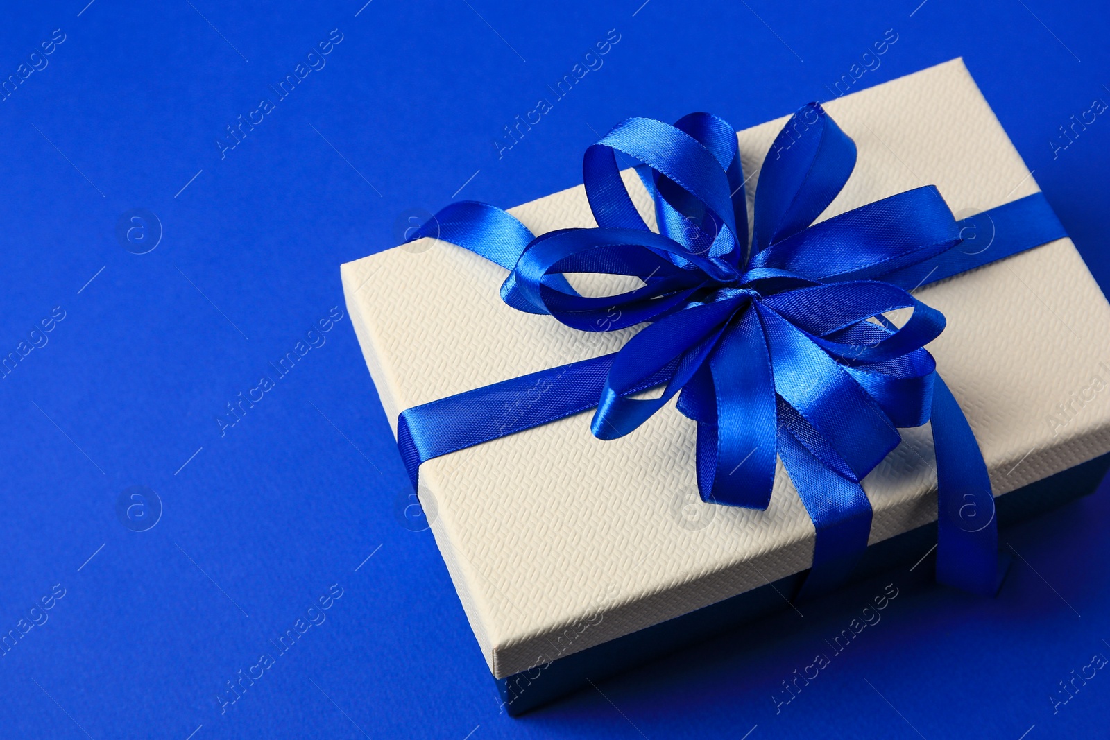 Photo of Beautiful gift box with bow on blue background