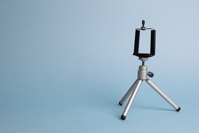 Photo of Modern stylish mobile tripod on light blue background. Space for text