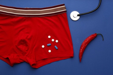 Photo of Flat lay composition with men's underwear and chili pepper on blue background. Potency problem concept