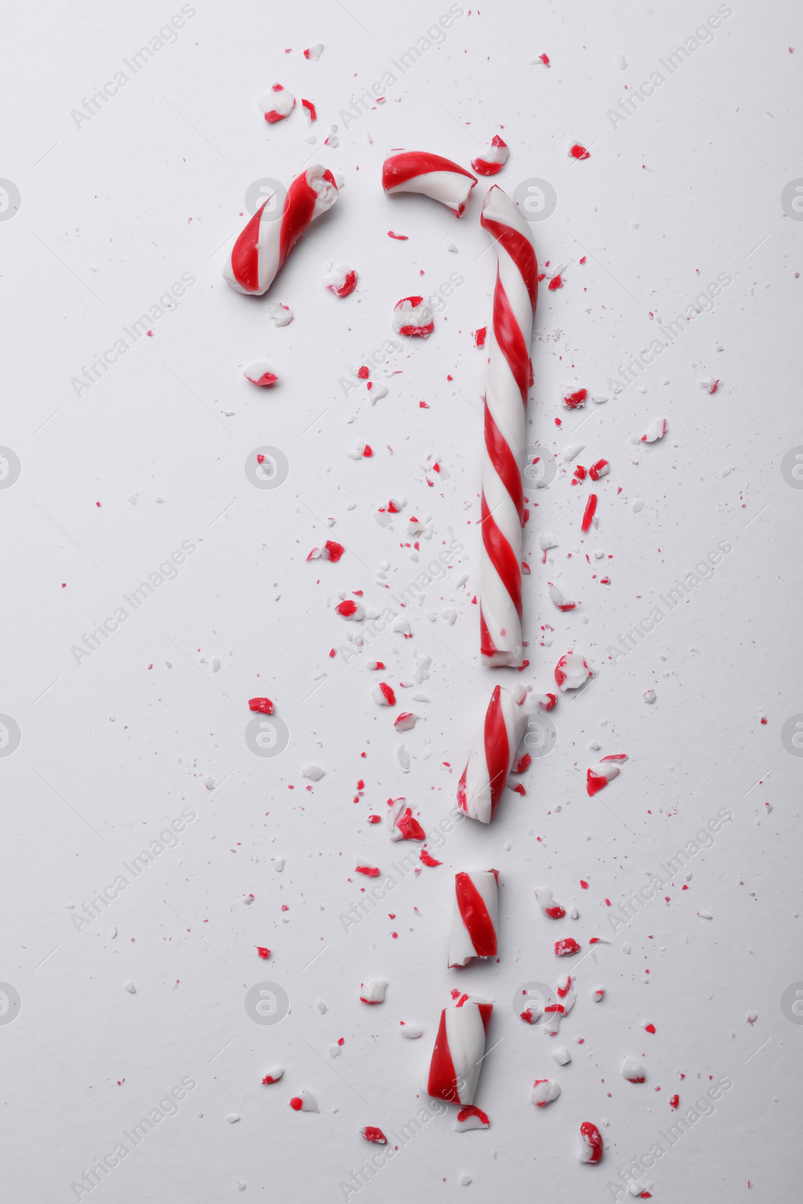 Photo of Broken sweet Christmas candy cane on white background, top view