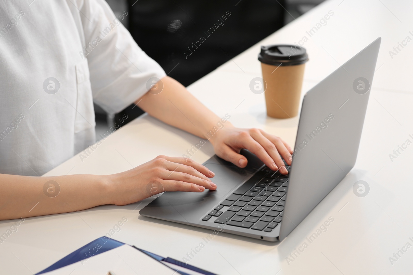 Photo of Woman working with laptop at white desk, closeup