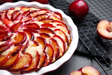 Photo of Delicious cake with plums on black table, closeup