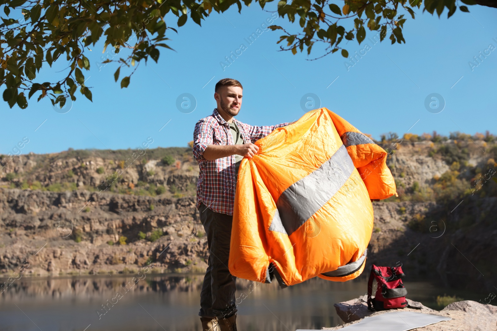 Photo of Young male camper with sleeping bag in wilderness