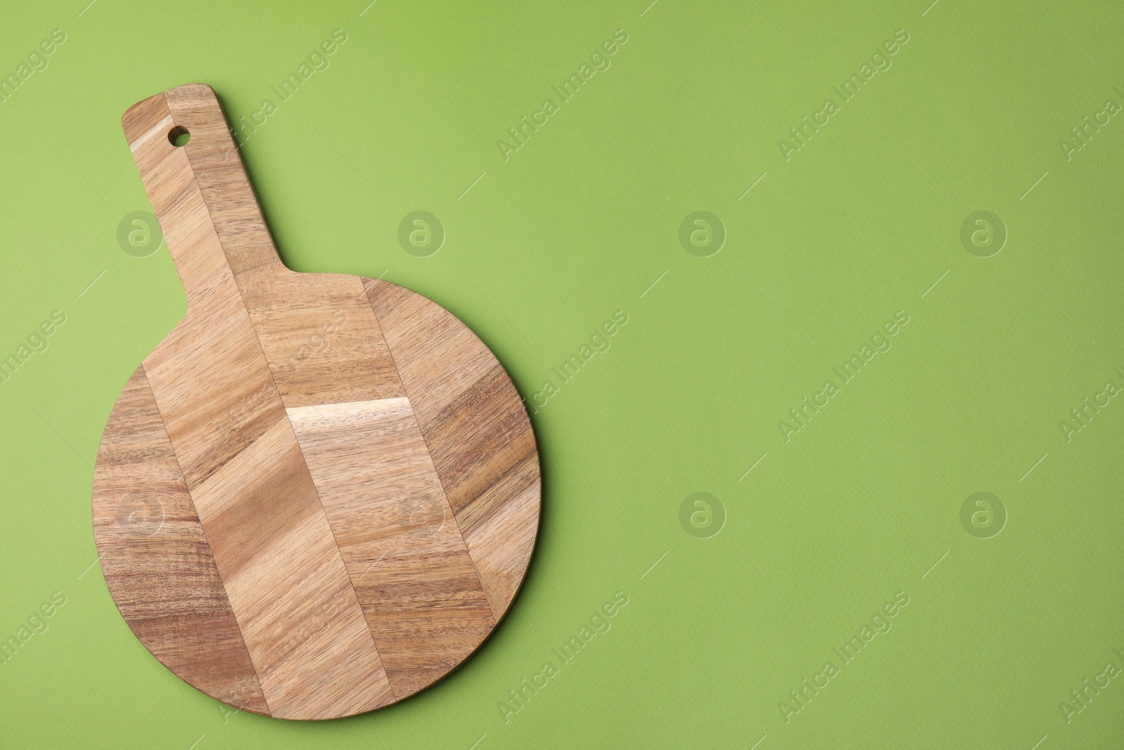 Photo of One wooden board on green background, top view. Space for text