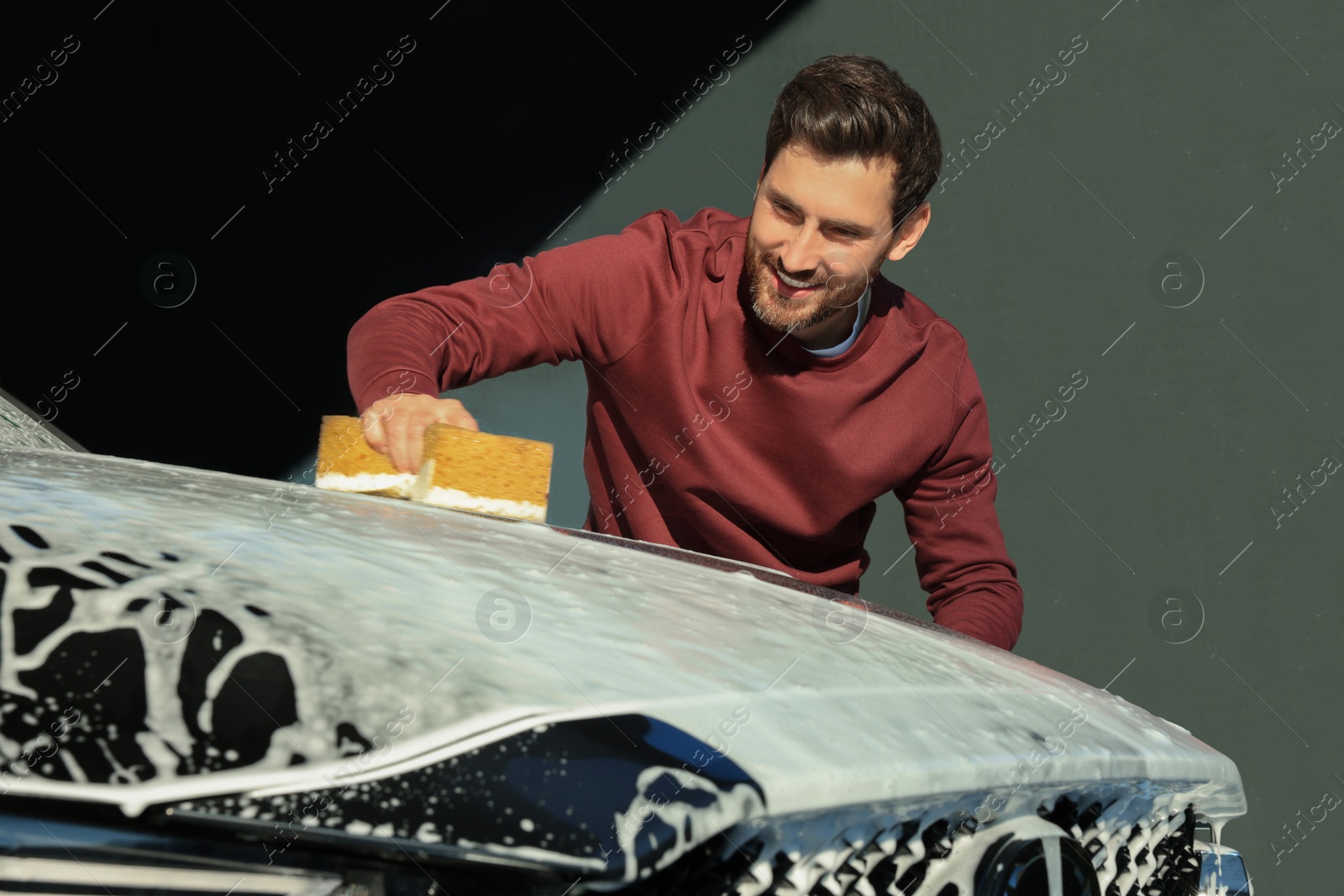 Photo of Worker washing auto with sponge at outdoor car wash