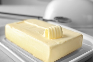 Dish with piece of butter and curl on table, closeup