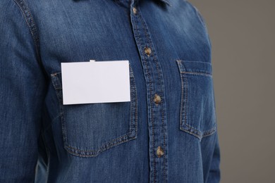 Woman with blank badge on grey background, closeup