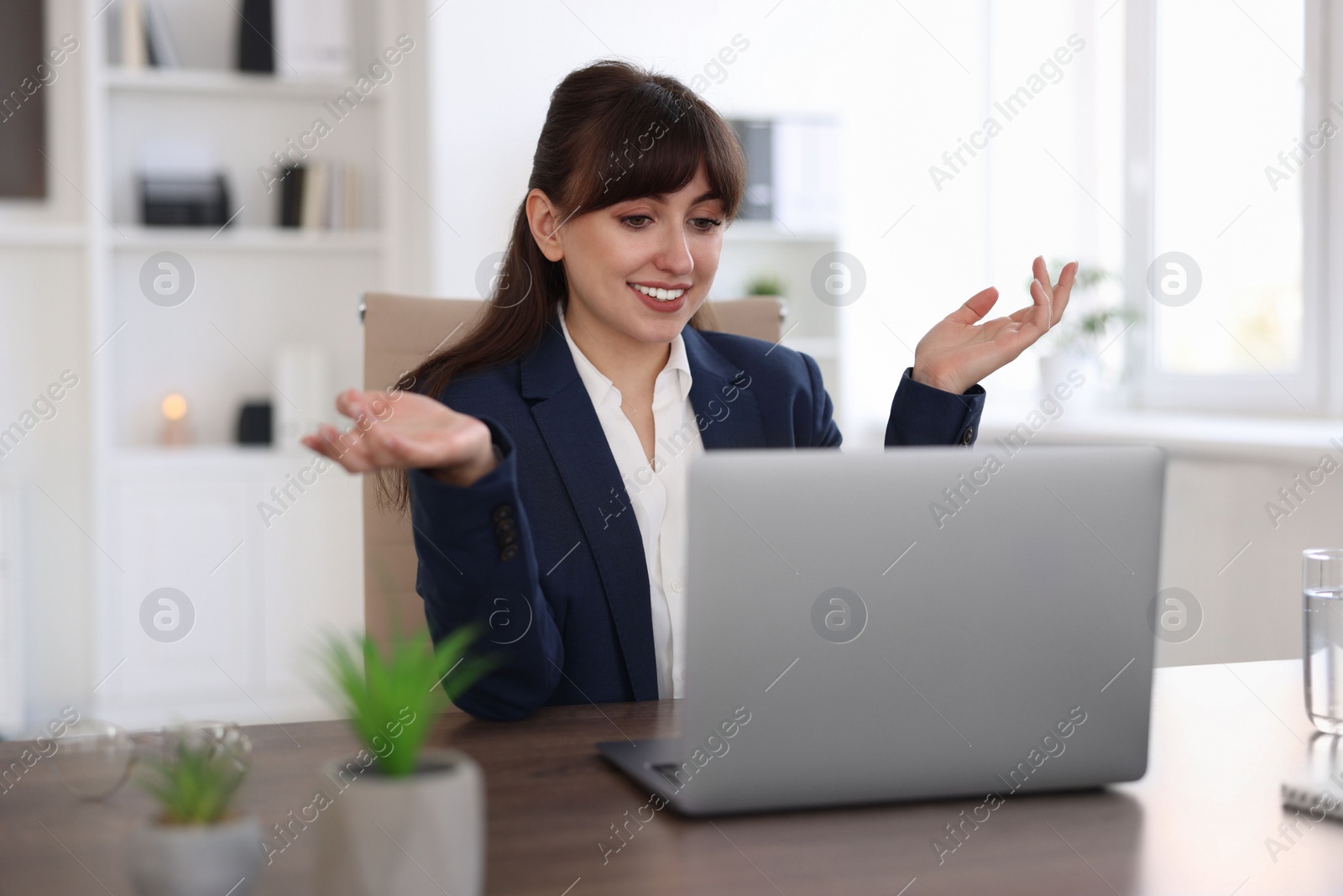 Photo of Woman using video chat during webinar at wooden table in office