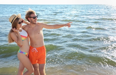 Photo of Happy young couple in beachwear spending time together at seashore on sunny day