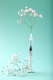 Cosmetology. Medical syringe and gypsophila flowers on turquoise background