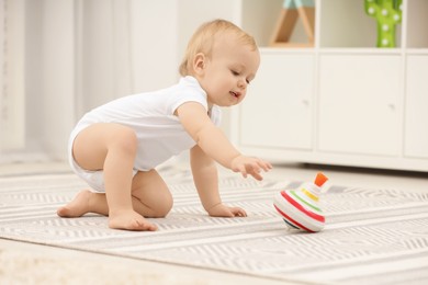 Children toys. Cute little boy playing with spinning top on rug at home