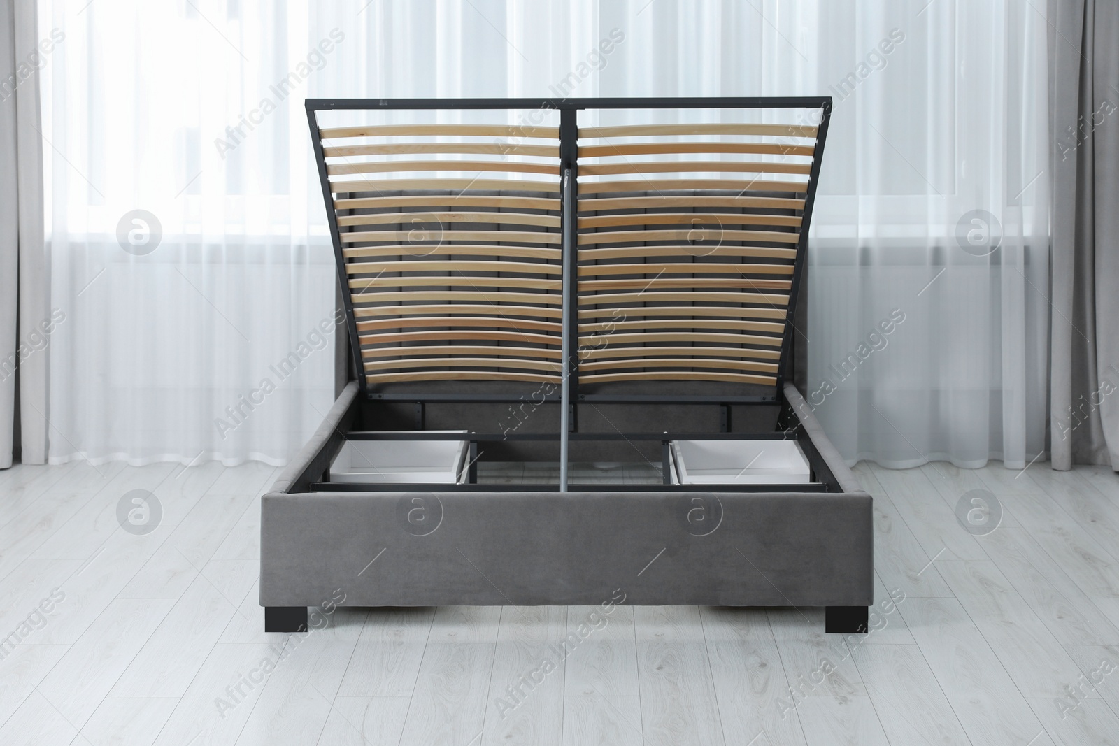 Photo of Modern bed with storage space for bedding under lifted slatted base in room