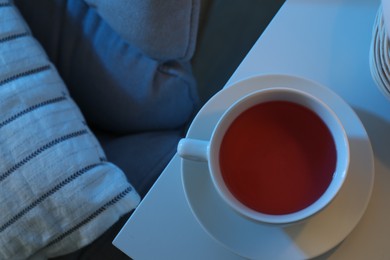 Cup of hot tea on white table at night, top view