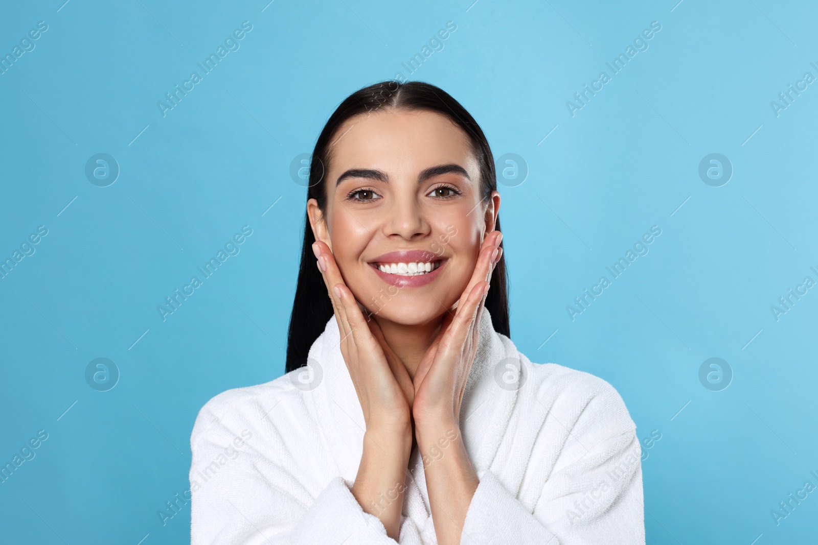 Photo of Portrait of attractive young woman in bathrobe on light blue background. Spa treatment