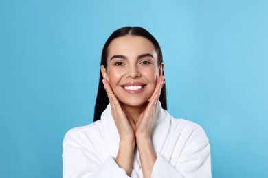 Portrait of attractive young woman in bathrobe on light blue background. Spa treatment