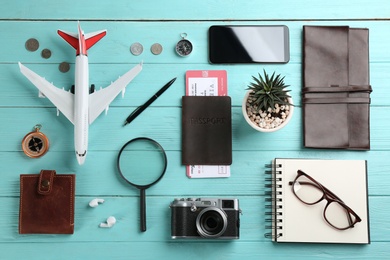 Photo of Flat lay composition with toy airplane and travel items on light blue wooden background