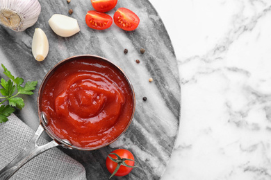 Flat lay composition with tomato sauce on marble background, space for text