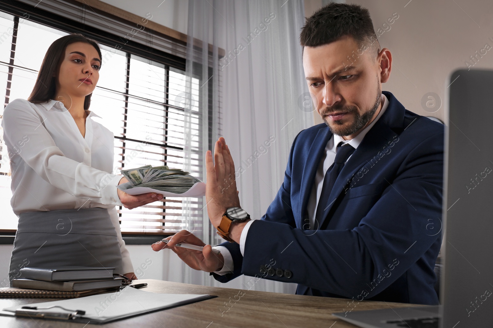 Photo of Businessman rejecting bribe at table in office