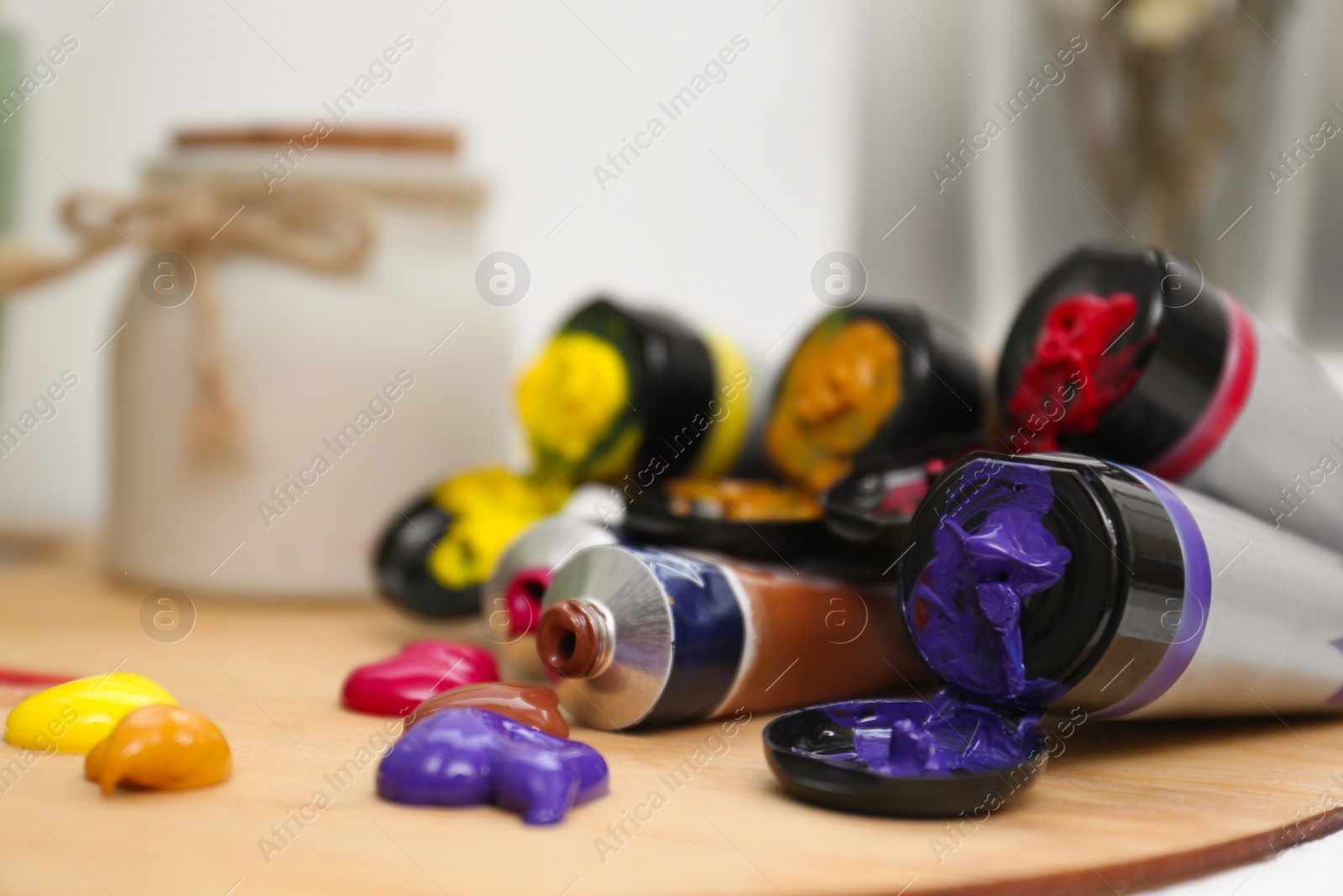 Photo of Wooden artist's palette and colorful paints on table, closeup. Space for text