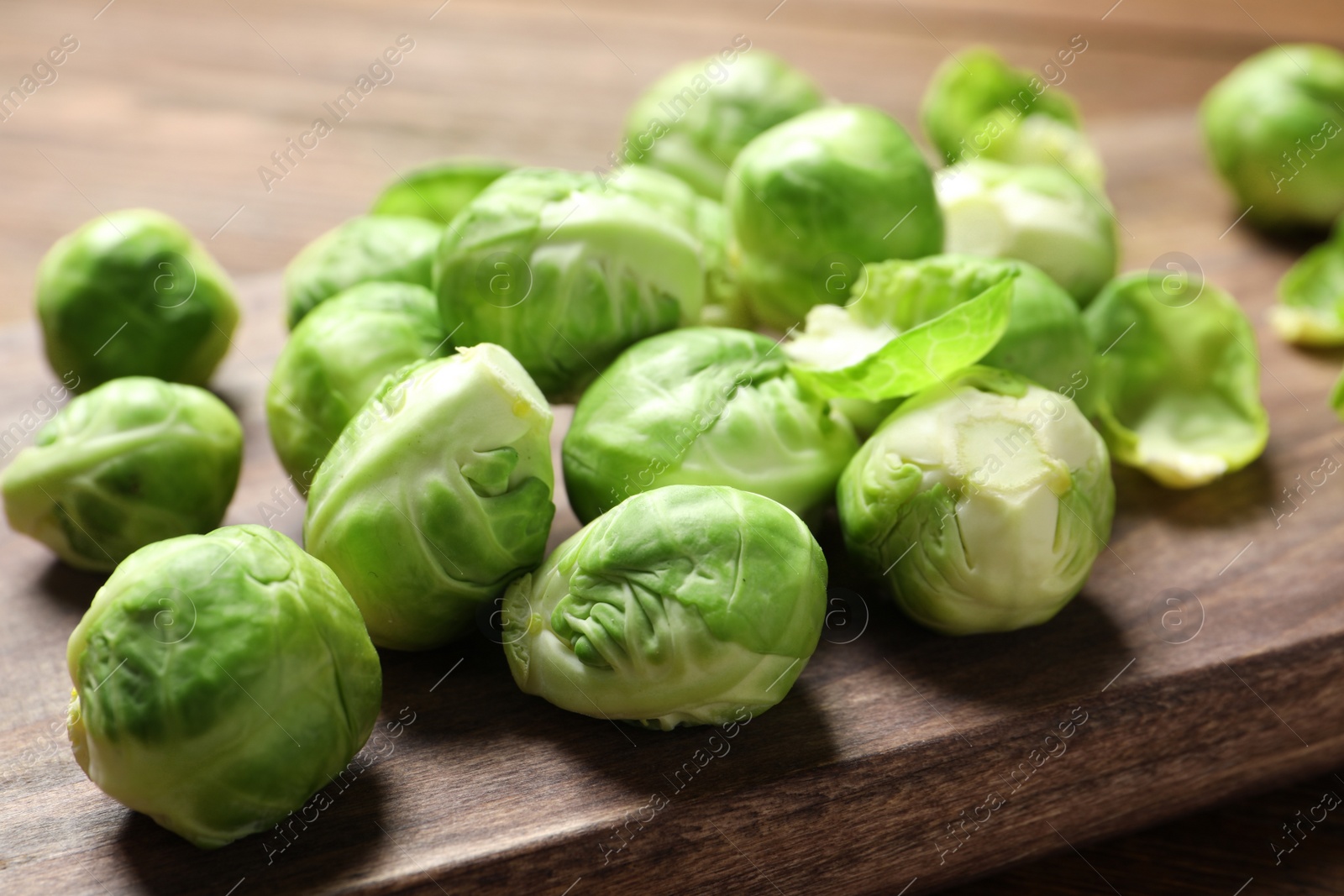 Photo of Wooden board with Brussels sprouts on table, closeup