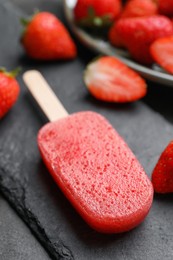 Photo of Tasty strawberry ice pop on dark table, closeup. Fruit popsicle