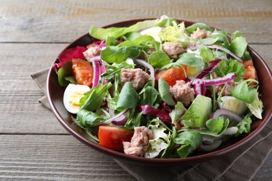 Bowl of delicious salad with canned tuna and vegetables on wooden table