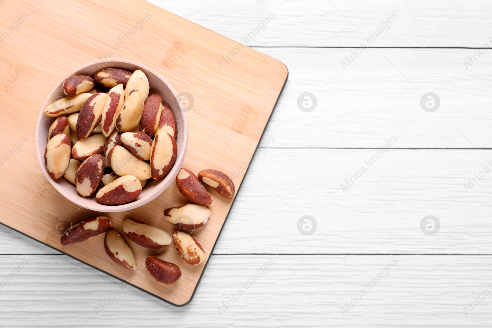 Photo of Delicious Brazil nuts on white wooden table, flat lay. Space for text