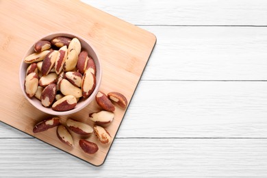 Delicious Brazil nuts on white wooden table, flat lay. Space for text