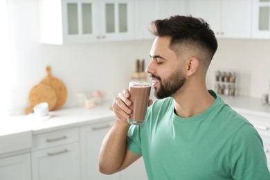 Photo of Young man drinking chocolate milk in kitchen
