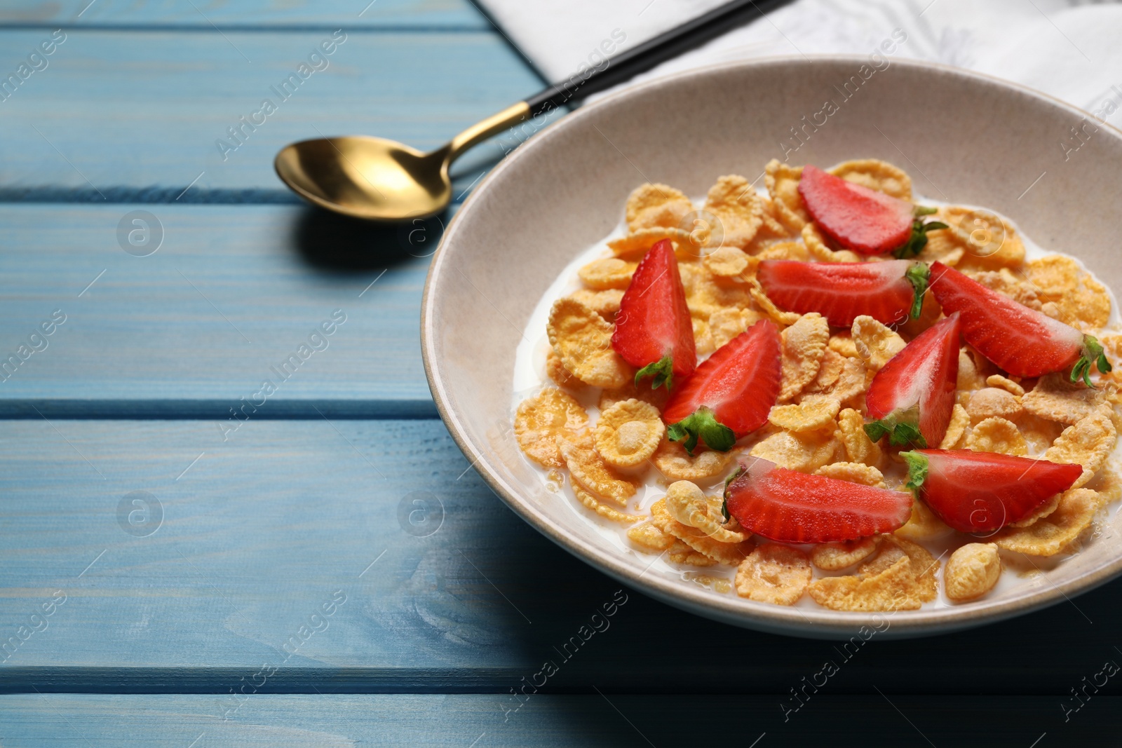 Photo of Delicious crispy cornflakes with milk and fresh strawberries on light blue wooden table, closeup. Space for text