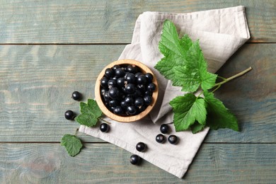 Ripe blackcurrants and leaves on wooden rustic table, flat lay