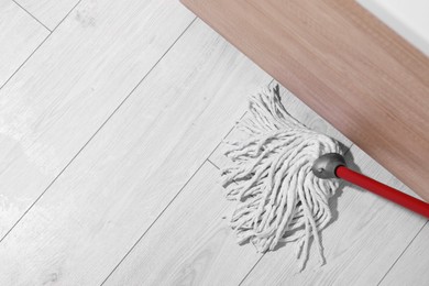 Photo of Cleaning dirty parquet floor with mop indoors, above view. Space for text