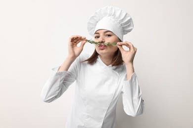 Photo of Professional chef with rosemary having fun on light background