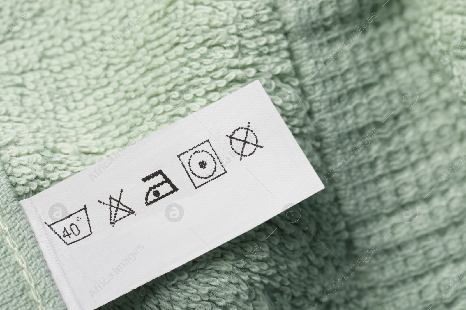 Photo of Clothing label on light green fluffy towel, top view