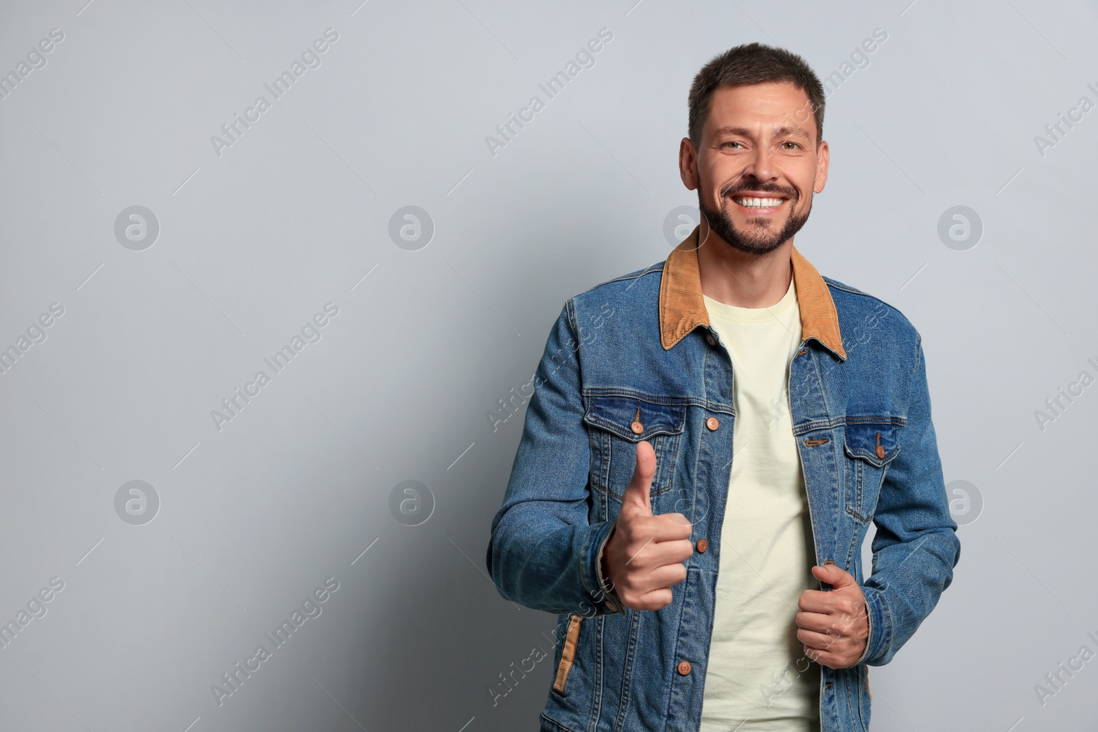 Photo of Man showing thumb up on grey background, space for text
