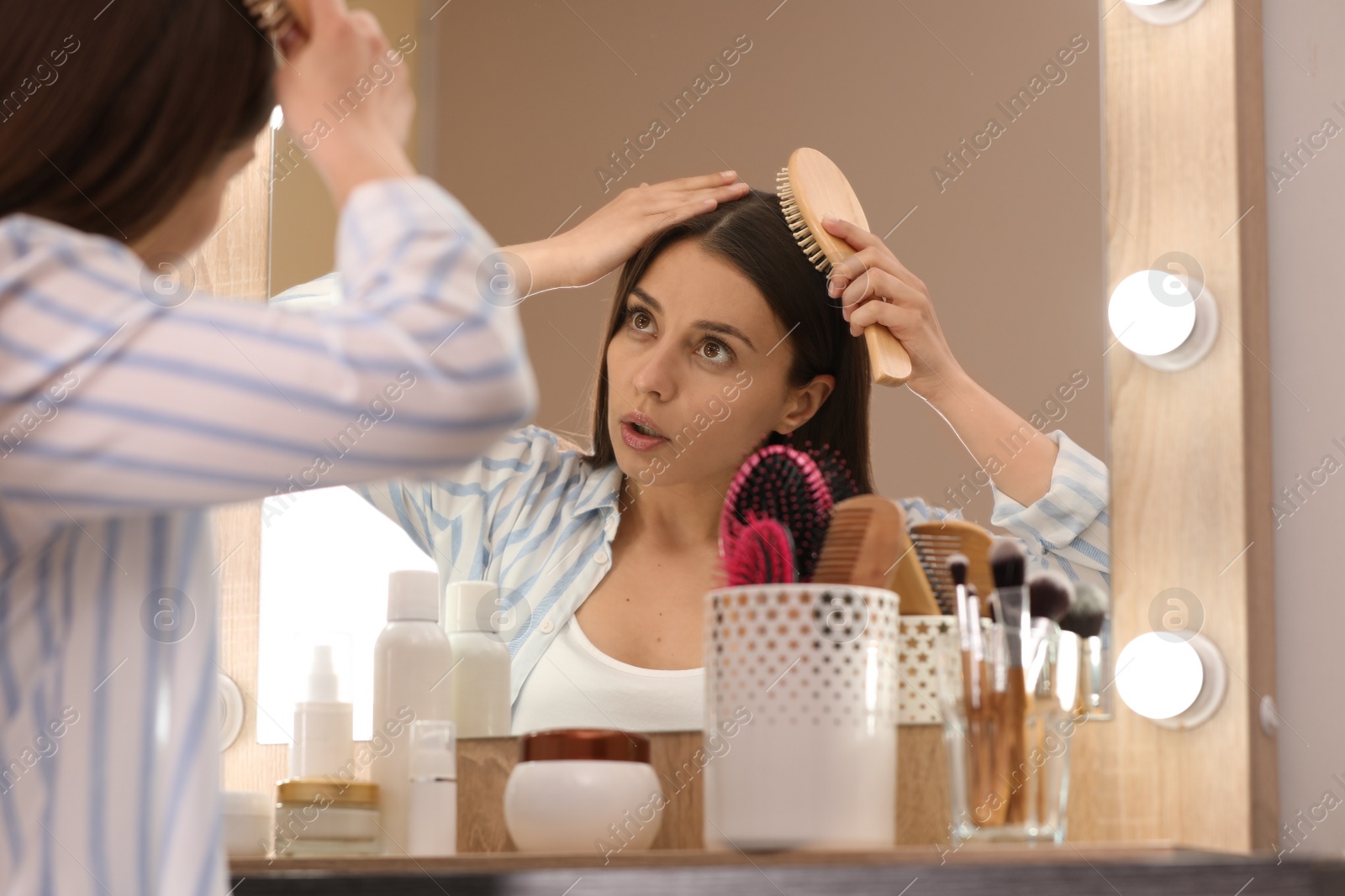 Photo of Young woman with hair loss problem near mirror indoors