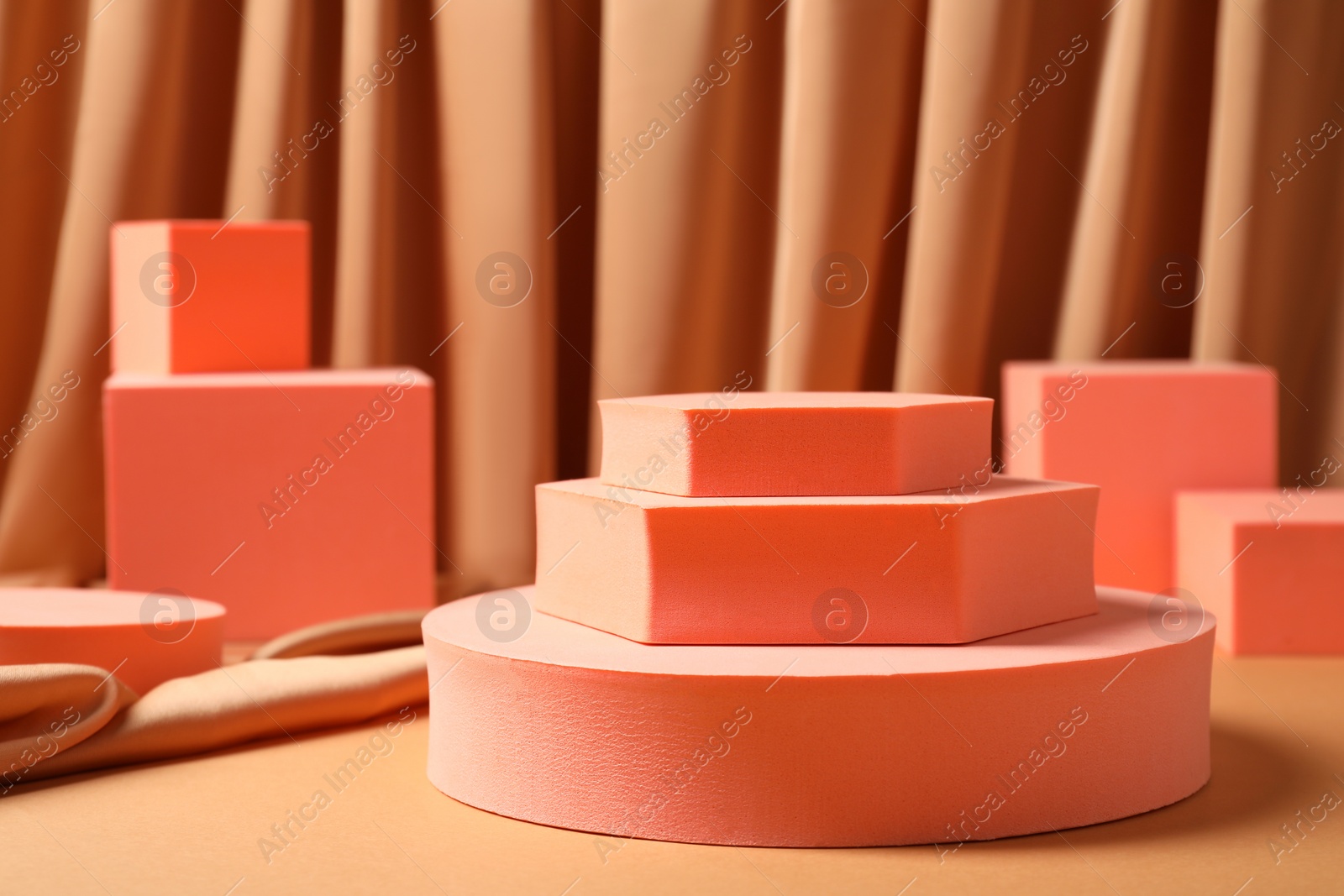 Photo of Geometric figures on table against light brown curtain. Stylish presentation for product