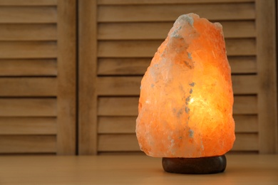 Photo of Himalayan salt lamp and space for text on wooden background