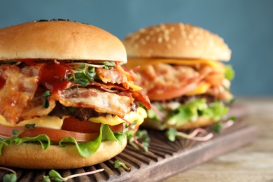 Photo of Tasty burgers with bacon served on table, closeup