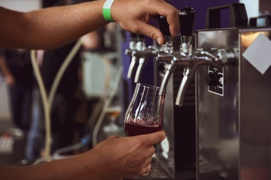 Photo of Bartender pouring beer into glass in pub, closeup