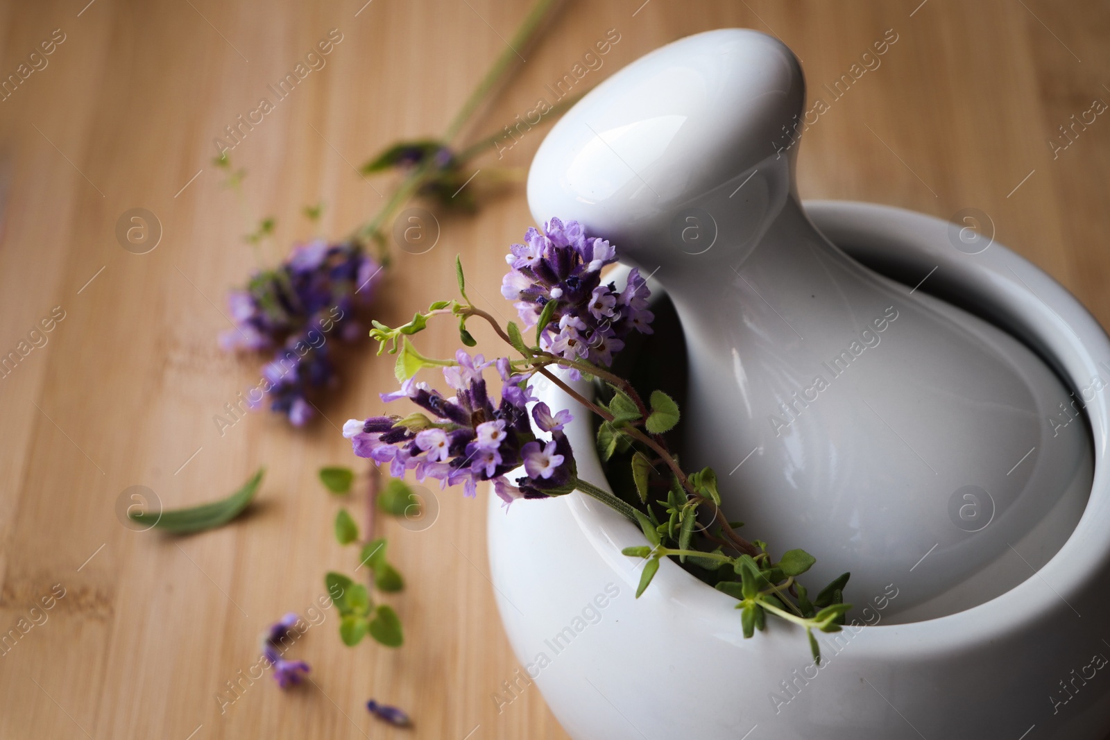 Photo of Mortar with fresh lavender flowers, green twigs and pestle on table, closeup. Space for text