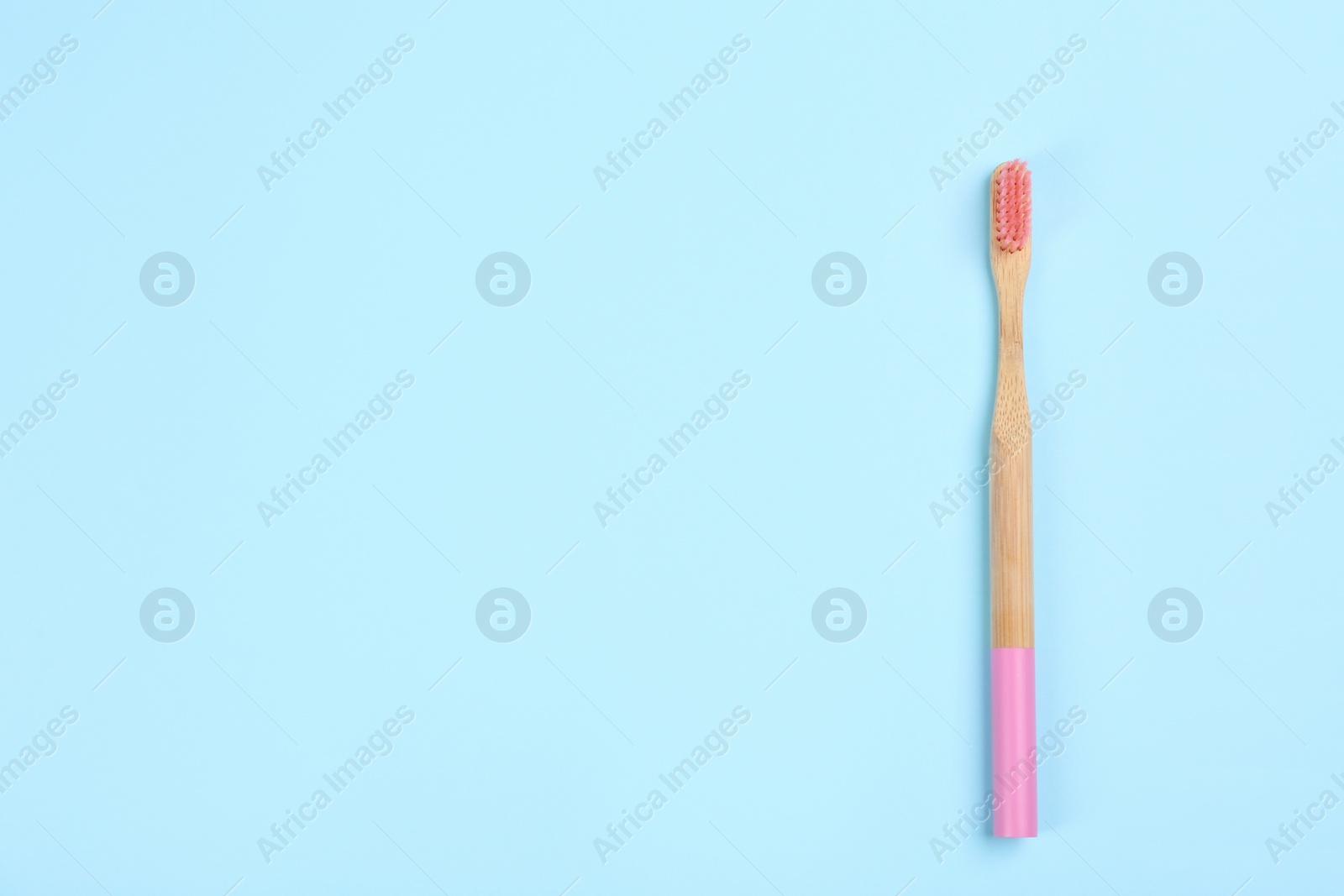 Photo of Toothbrush made of bamboo on light blue background, top view. Space for text