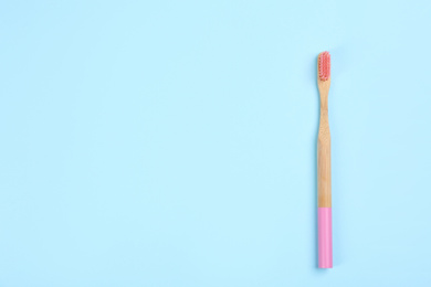 Photo of Toothbrush made of bamboo on light blue background, top view. Space for text