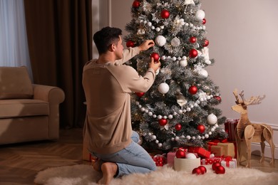 Photo of Man decorating beautiful Christmas tree at home
