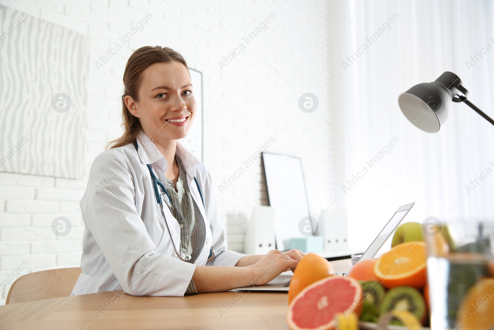 Photo of Nutritionist working with laptop at desk in office