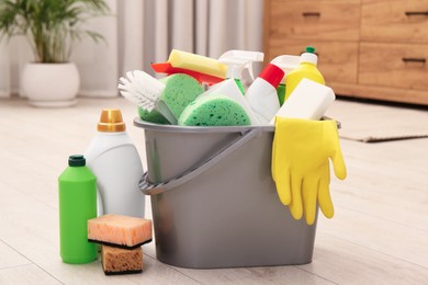 Different cleaning supplies in bucket on floor
