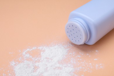 Photo of Bottle and scattered dusting powder on pale coral background. Baby cosmetic product