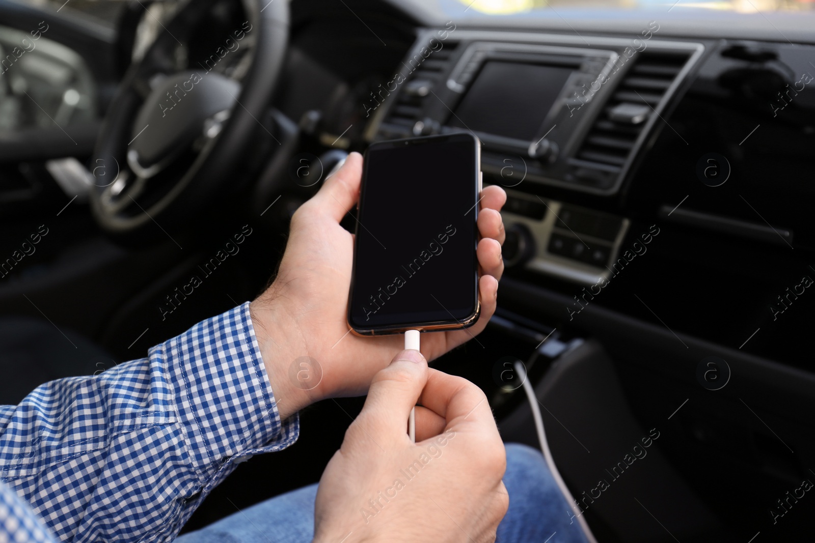 Photo of Man charging phone with USB cable in car