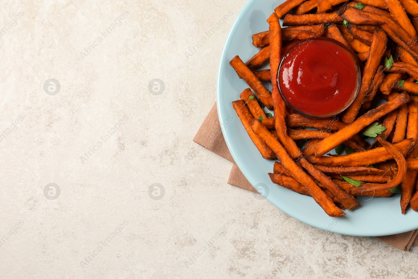 Photo of Delicious sweet potato fries served with sauce on light table, top view. Space for text